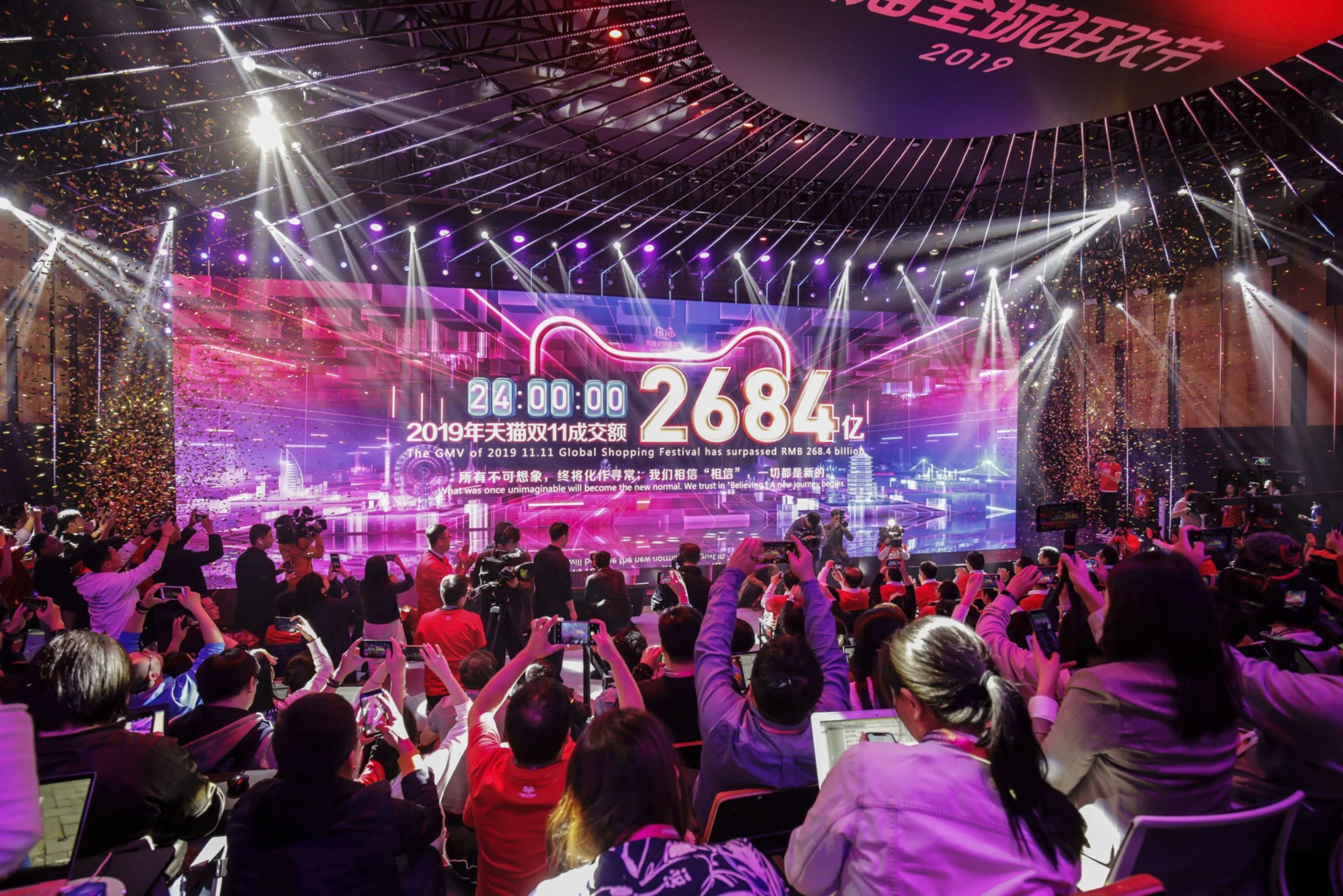 Members of the media and guests take photos with their phones at a screen showing the Gross merchandise value traded on various Alibaba platforms during the 11.11 shopping festival in Hangzhou, China on Monday 11 November 2019.