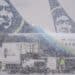 Worker next to Alaska Airlines planes during a snow storm at Seattle-Tacoma International Airport (SEA) in Seattle, Washington, US, on Tuesday, Dec. 20, 2022. An estimated 112.7 million people will travel 50 miles or more from Dec. 23 to Jan. 2, up by 3.6 million from last year and getting close to pre-pandemic levels, according to AAA, a provider of travel insurance. Photographer: David Ryder/Bloomberg