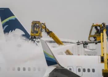 Workers deice an Alaska Airlines plane during a snow storm at Seattle-Tacoma International Airport (SEA) in Seattle, Washington, US, on Tuesday, Dec. 20, 2022. An estimated 112.7 million people will travel 50 miles or more from Dec. 23 to Jan. 2, up by 3.6 million from last year and getting close to pre-pandemic levels, according to AAA, a provider of travel insurance. Photographer: David Ryder/Bloomberg