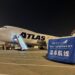 An Atlas Air airplane sits on the tarmac alongside cargo