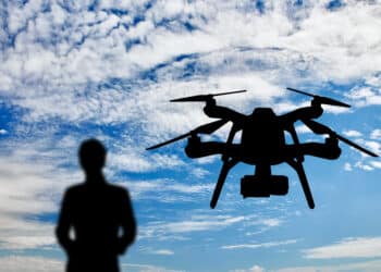 Silhouette Of A Flying Drone, And A Man With A Remote Control