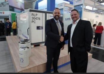 Miguel Rodriguez and Akos Balkanyi shake hands in front of an Envirotainer container