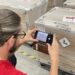 A man uses a cell phone to check labels on a cargo shipment