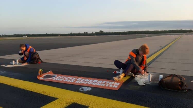 Members of German activist group Letzte Generation stick themselves to the tarmac at Hamburg Airport.