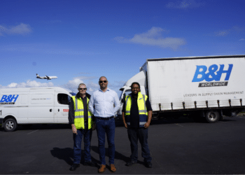 Three men stand in front of B&H vehicles