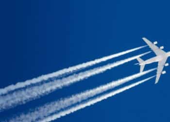 Airplane flying in sky with contrails behind it