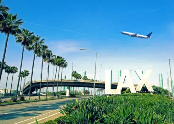 Exterior shot of LAX with plane in the air above it