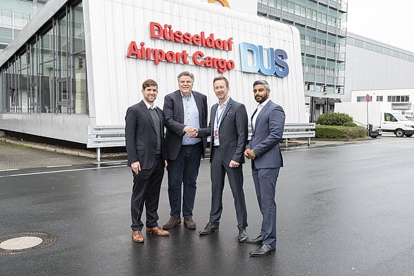 Four men stand outside a Dusseldorf Airport Cargo building