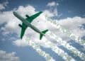 Aircraft soars through the sky leaving jet contrails with green leaves