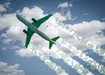 Aircraft soars through the sky leaving jet contrails with green leaves