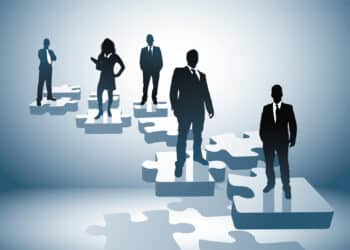 Silhouettes of executives standing aboard puzzle pieces