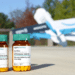 In the foreground, two medicine bottles and, in the background, an out-of-focus Amazon drone