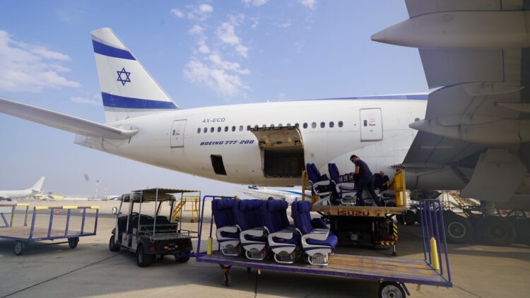 Passenger seats sit on a trolley, being taken away from a plane with the Israeli flag on its tail