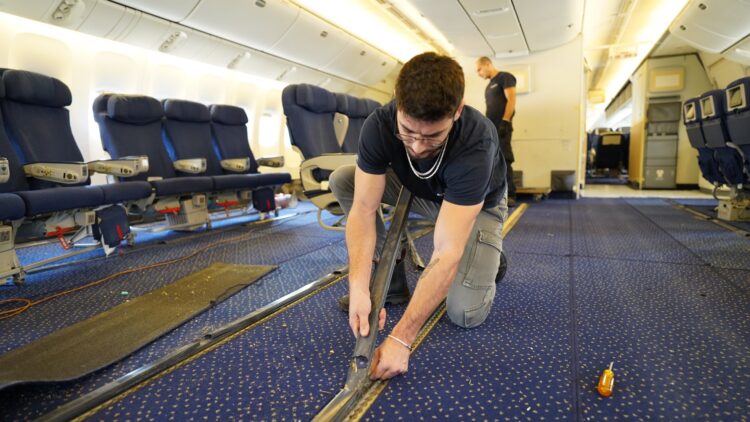 A man works to remove seats from a passenger plane