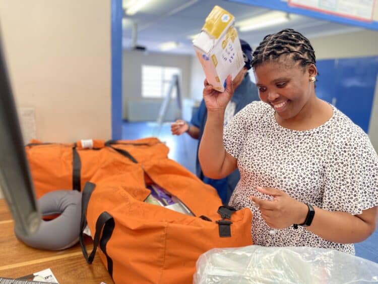 A woman packs nursing supplies into an orange duffel bag
