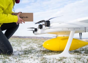 A man holds a box alongside a cargo drone