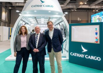 Three people stand in front of a mock Cathay Cargo airplane