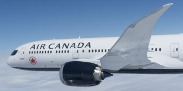 An Air Canada plane flies in a blue sky
