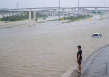 A man looks at a flooded highway