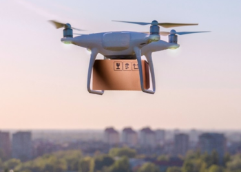 A drone carrying a package flies over a city with a river