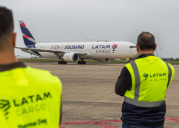 Two LATAM Airlines employees watch a LATAM Cargo plane on the tarmac